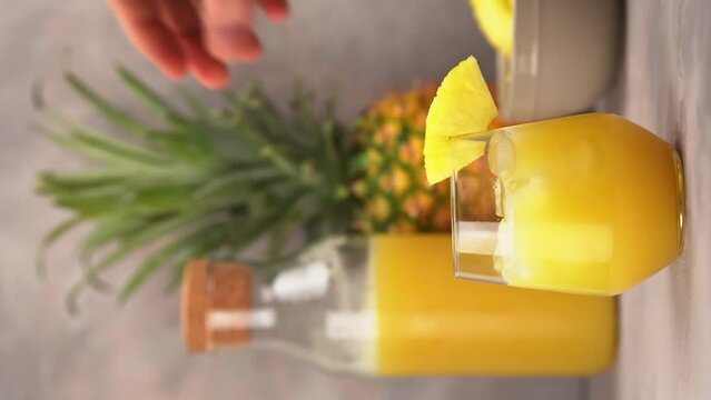Rum cocktail with pineapple juice. Barman decorating with pineapple slice a cocktail. Vertical Video
