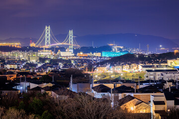 Suspension Bridge Towers Over Houses in Residential Neighborhood at Night