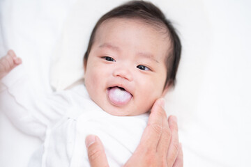 ミルクかすが付いた舌を出して可愛らしい笑顔を見せる生まれたての赤ちゃん