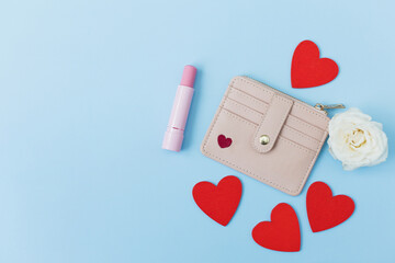 Pink wallet, lipstick on blue background