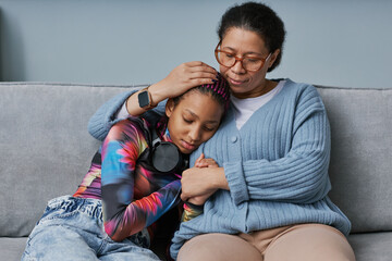 Black mother embracing teenage daughter