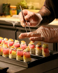 Hand of chef making decoration sushi roll.