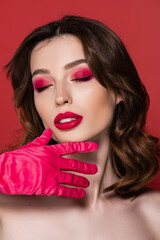 young woman with magenta color eye shadow posing with closed eyes isolated on pink.