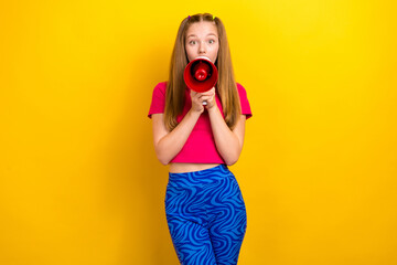 Portrait of impressed positive girl with long hairdo dressed pink top shout news hold loudspeaker isolated on yellow color background