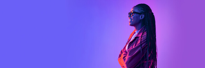 Cheerful african woman in glasses posing, looking away with smile over gradient blue purple...