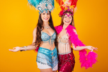 two brazilian female friends with queen clothes from samba school, carnival. Feather crown. welcome.