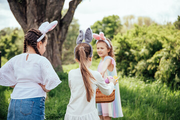 Easter egg hunt. Group Of Children Wearing Bunny Ears Running To Pick Up colorful Egg On Easter Egg Hunt In Garden. Easter tradition