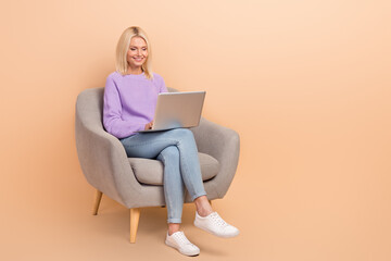 Full size photo of positive woman purple sweater jeans on armchair look at laptop remote meeting...