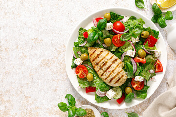 Grilled chicken fillet and fresh green leafy vegetable salad with tomatoes, red onion, olives and feta cheese. Healthy food. Ketogenic lunch. Top view