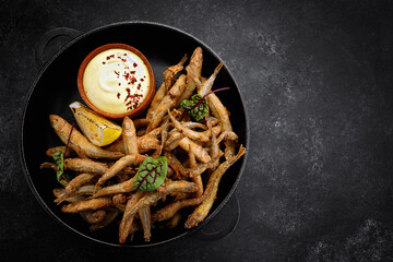 Fried fish with sauce, appetizer, on gray concrete