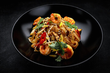 Pasta with shrimp and vegetables, Asian food. black plate