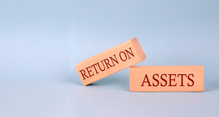 RETURN ON ASSETS text on the wooden block, blue background