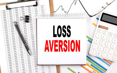 LOSS AVERSION text on notebook with chart, calculator and pen