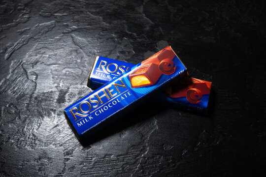 LVIV, UKRAINE - January 25, 2023 : Roshen Milk chocolate bar on black background. Ukrainian confectionery manufacturing.