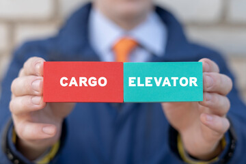 Cargo elevator business industry concept. Businessman holding colorful blocks with inscription: CARGO ELEVATOR.