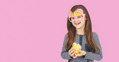 A wide smiling caucasian girl with little chicken on pink background. Baby chicks in child hands. Easter to the child. Easter day. Copy space