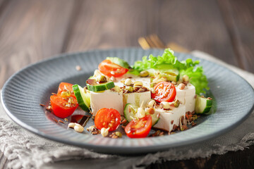 Feta cheese in cubes and vegetables - tomatoes and cucumbers in a plate. Light Greek salad with seedlings
