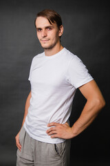 Young man in a white t-shirt on a gray background.