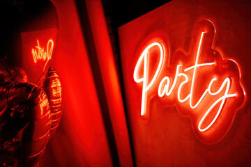 Party neon led sign board on wall by graphic font at valentines day celebration with heart balloons