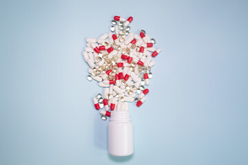 White medicine bottles, red and white pills,  tablets, white pills and red pills on a blue background, modern medicine used to prevent and treat diseases, copy space.