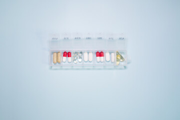 Daily pill box with medical pills isolated on blue background with copy space for your text. Top view. Flat lay