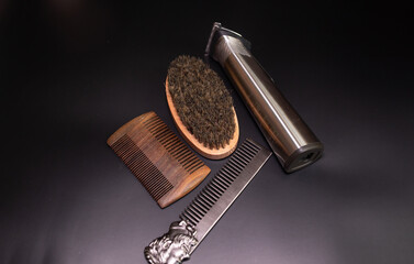 Man beard grooming items on a black background, wooden comb,  oil, brush and electric trimmer