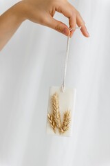 Aromasache with dried flowers with coconut or organic soy wax. in hand on a white background