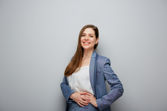 Smiling business woman in blue suit. Female portrait near gray wall.