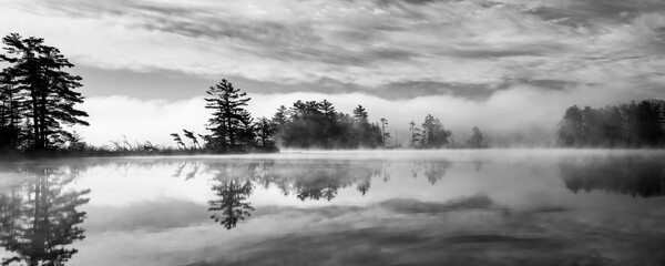 Mist and fog and clouds mix together to create a surreal sunrise scene on a Northwoods lake.  Oneida County, WI.