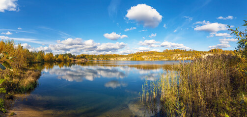 Fototapeta premium Snow-white clouds are reflected in the lake in autumn.