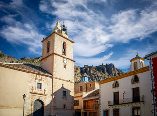 Fototapeta na wymiar Town square in Blanca, Murcia, Spain, with the church and some unique palaces with the mountains in the background