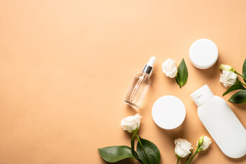 Obraz na płótnie Canvas Natural cosmetic products at color background. Cream, serum, tonic with green leaves and flowers. Flat lay image with copy space.