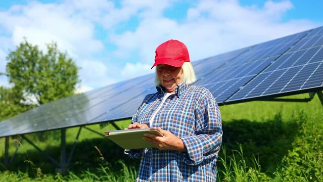 An female engineer is checking with tablet an operation of sun and cleanliness on field of photovoltaic solar panels on a sunset. Technology, electricity, service, green, future 