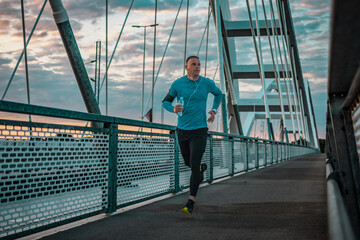 Morning run over the bridge. Fitness, sport and recreation. Sports man jogging and listen the music.
