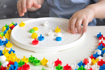 Obraz na płótnie Canvas Little child playing with mushroom nail mosaic constructor.