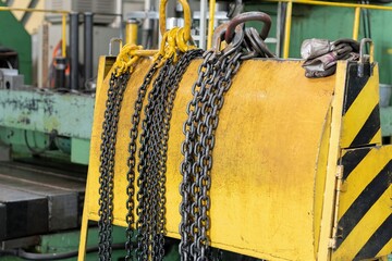 Yellow storage rack for chain slings for lifting loads on a crane.