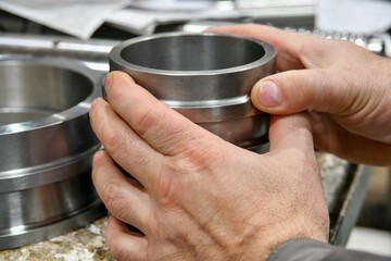 A worker holds the sleeve after cnc machining to measure and check for accuracy.