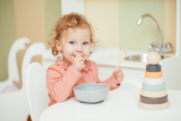 Little baby eats pasta in the children's kitchen