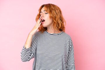 Young caucasian woman isolated on pink background yawning and covering wide open mouth with hand