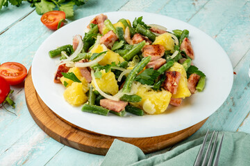 Traditional European potato salad with bacon and beans dressed with olive oil, Liege salad. Close-up.