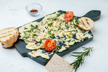 A trendy word butter appetizer served on a wooden board with herbs and spices and a baguette. Light background.