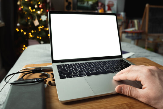 Man using a laptop with a blank white screen. Remote work at home concept. Mockup. Copy space. Home interior design. Close up of man surfing the internet using a touchpad