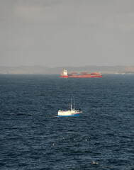 Cargo and fishing ships on a collision course in the blue sea - 565416942