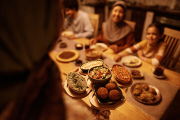 Close up of Middle Eastern woman serving food for dinner to her family.