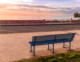 Fototapeta na wymiar metallic bench on sea embarkment with asphalt road and beautiful seashore landscape with amazing cloudy sky