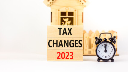 Tax changes 2023 symbol. Concept words Tax changes 2023 on wooden blocks on a beautiful white table white background. Black alarm clock, house model. Business Tax changes 2023 concept. Copy space.