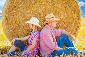 happy couple on the field with bales harvest in autumn