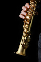Obraz premium soprano saxophone in hands on a black background