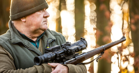 Fototapeta premium Portrait of hunter or ranger with a hunting gun and hunting form to hunt in an autumn forest, hunting concept