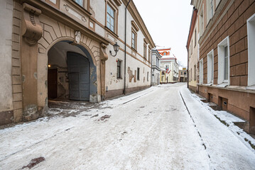 Winter view of the short, narow and winding historic Bernardinu street in Old Town of Vilnius, Lithuania - obrazy, fototapety, plakaty